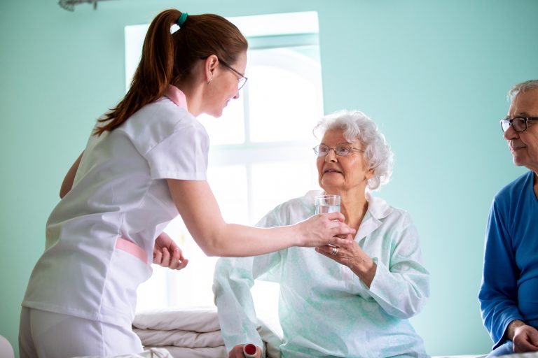 caregiver giving water to patient in a long term care HFG Trust